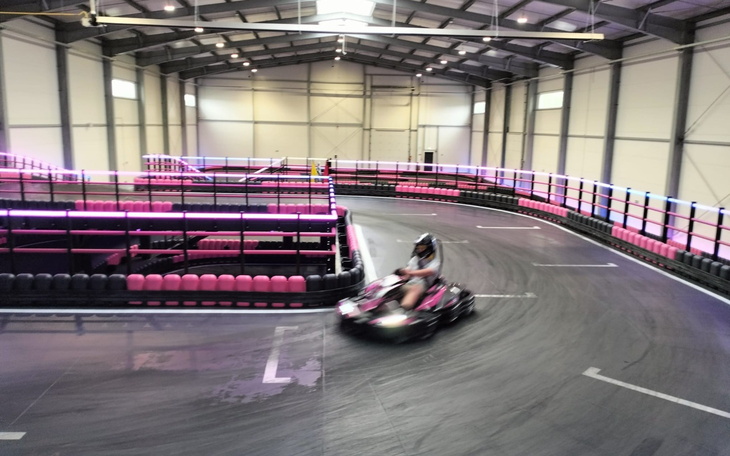 Go-kart na torze wyścigowym z różowymi i niebieskimi światłami.