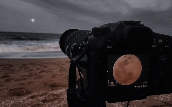 Aparat fotograficzny uchwycił pełnię księżyca nad morzem.