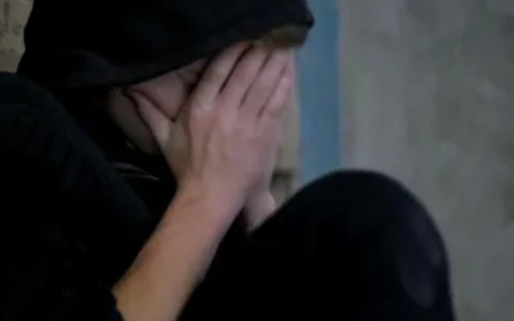 Młody człowiek z twarzą w dłoniach, wyrażający smutek.