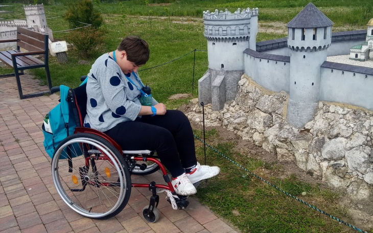 Osoba na wózku inwalidzkim przy miniaturowym zamku.