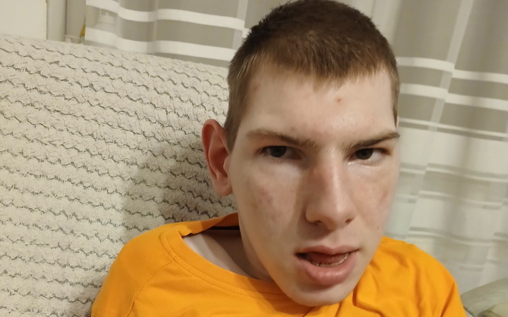 Młody chłopak z wyrazem twarzy, siedzący na kanapie.