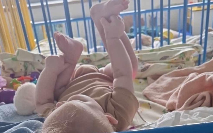 Małe dziecko leżące w łóżeczku, bawiące się nóżkami.