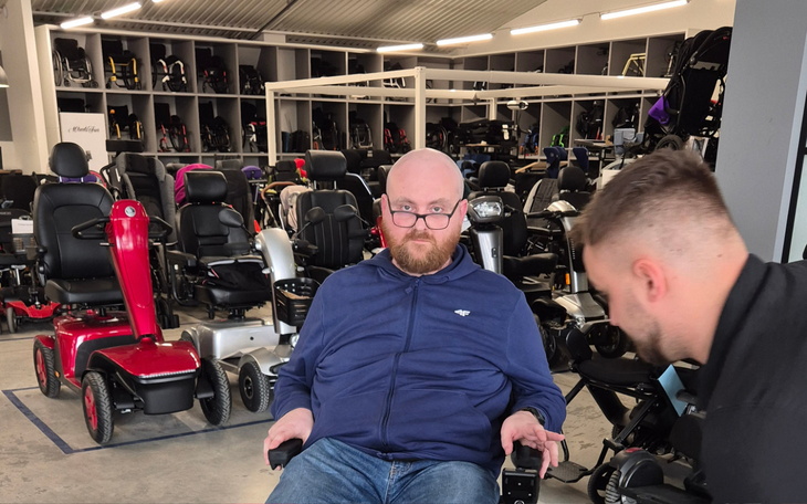 Mężczyzna testujący wózek inwalidzki w sklepie.