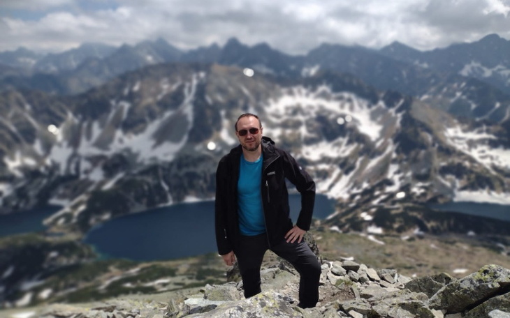 Mężczyzna na szczycie góry z widokiem na jezioro.