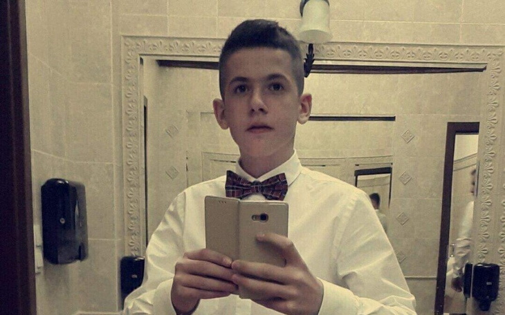 Młody mężczyzna w eleganckim stroju, robiący selfie w lustrze.