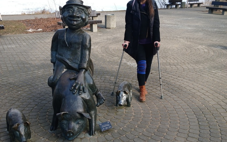 Kobieta przy rzeźbie mężczyzny z psami na placu.