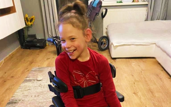 Uśmiechnięta dziewczynka w wózku, radosna i pełna energii.