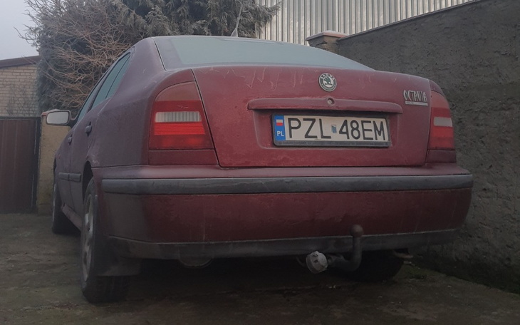 Stary, brudny samochód zaparkowany na podwórku.