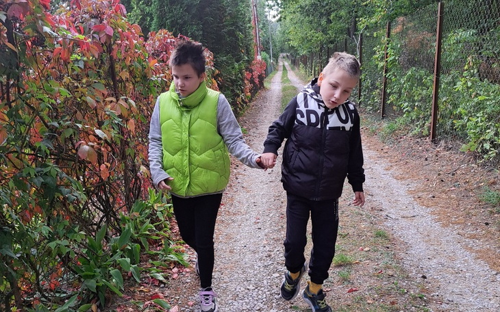 Dwoje dzieci spacerujących po leśnej ścieżce.