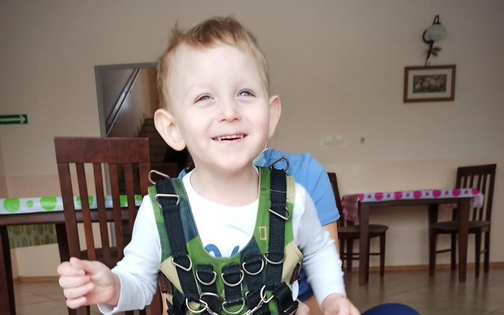 Uśmiechnięty chłopiec w kamizelce, bawiący się.