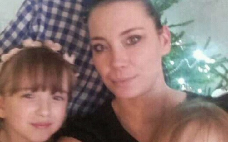 Kobieta z dzieckiem, obie uśmiechnięte, w przytulnej scenerii.