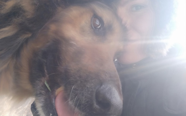 Pies i jego właścicielka, oboje uśmiechnięci.