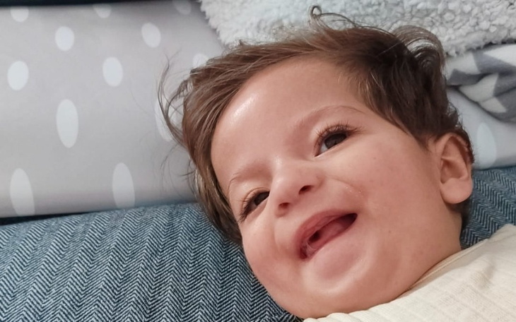 Uśmiechnięte dziecko leżące na poduszce.
