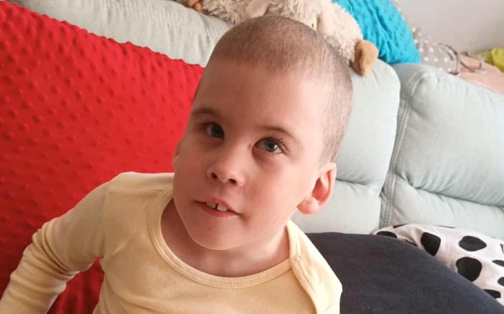 Chłopiec z krótkimi włosami siedzący na kanapie.