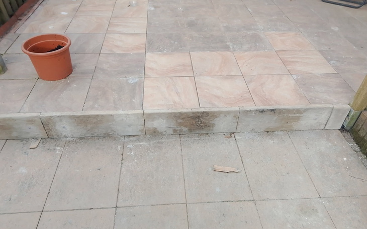 Widok na taras z płytkami i doniczką na rośliny.