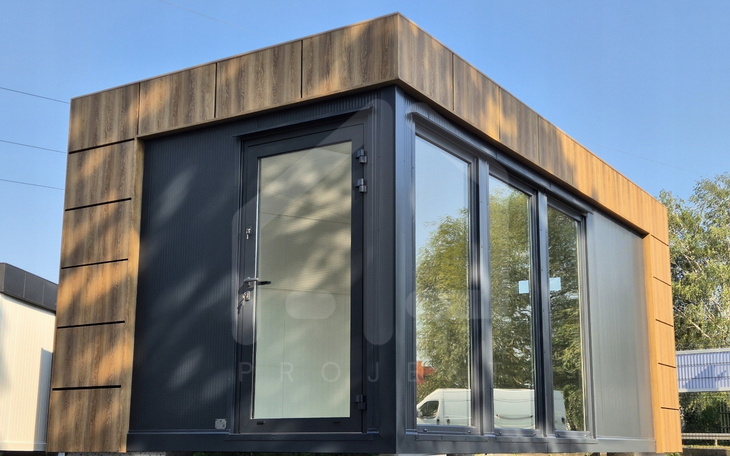 Nowoczesny domek z dużymi oknami, otoczony zielenią.