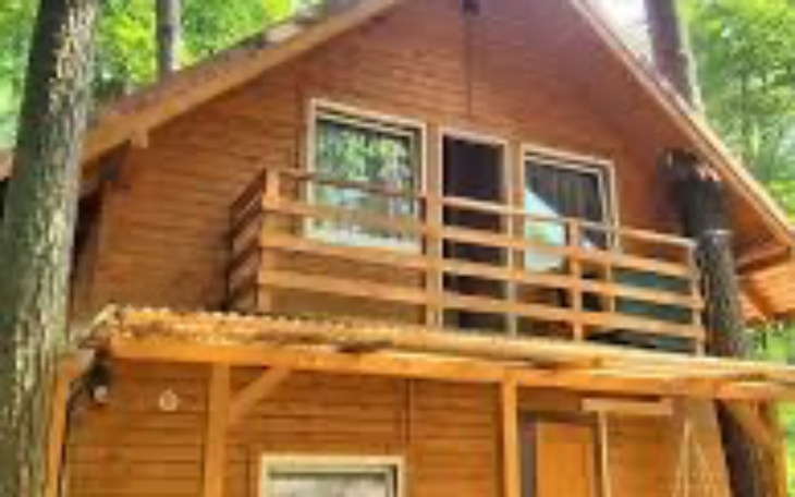 Domek w lesie, z balkonem i otoczeniem drzew.