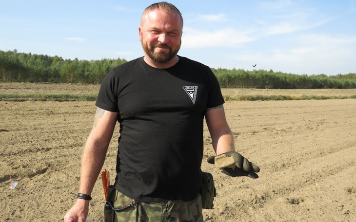 Mężczyzna w polu, trzymający rękawicę roboczą.