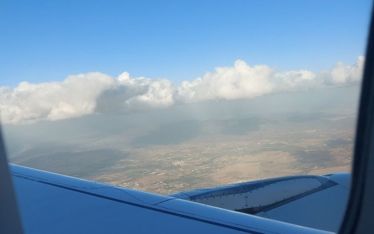 Widok z okna samolotu na chmury i krajobraz.