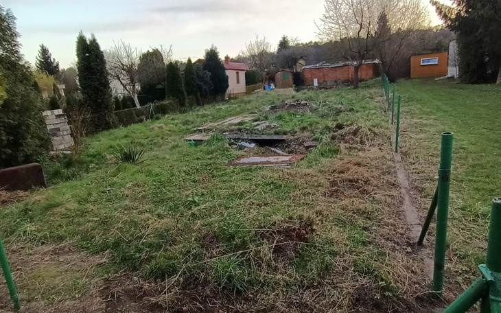 Zarośnięta działka z widocznymi resztkami budowy.