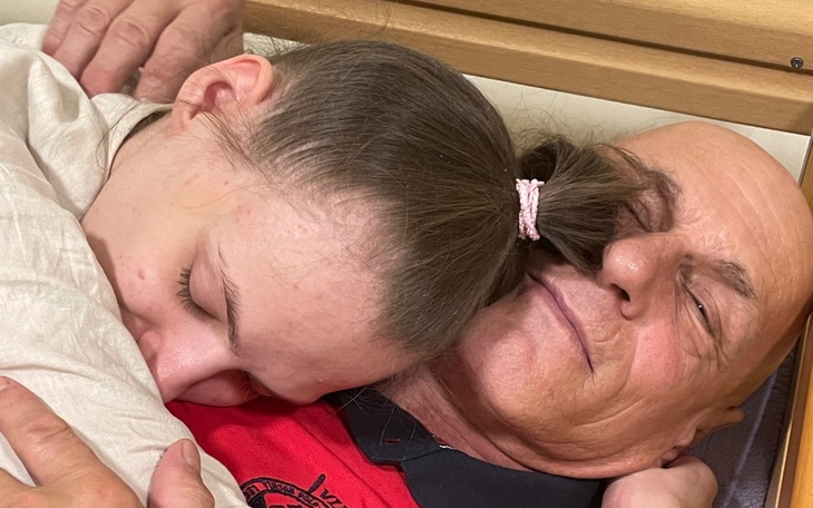 Dziecko śpiące na ramieniu starszego mężczyzny, oboje wyglądają na zrelaksowanych.