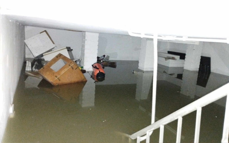 Zalane pomieszczenie z meblami unoszącymi się na wodzie.