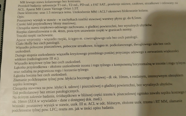 Kot z opatrunkiem na łapie, leżący na szarej powierzchni.