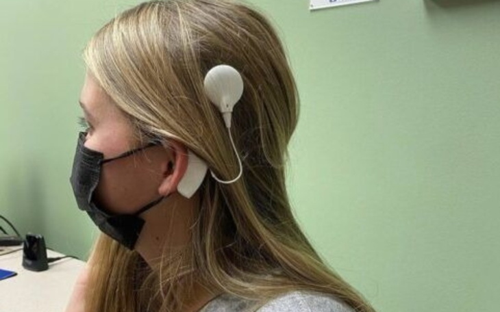 Młoda kobieta z urządzeniem medycznym na uchu.