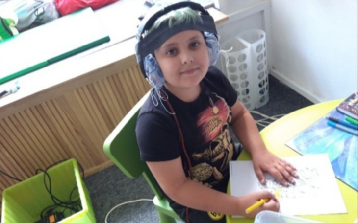 Chłopiec rysujący przy biurku, z słuchawkami na uszach.