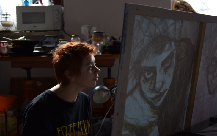 Artystka przy obrazie, skupiona na swojej pracy twórczej.