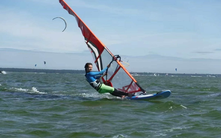 Mężczyzna uprawiający windsurfing na wodzie w słoneczny dzień.