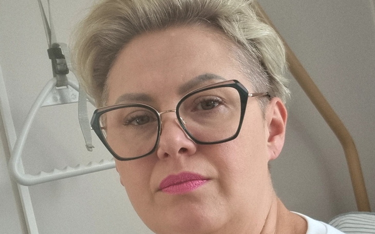 Kobieta z okularami i różową szminką w szpitalu.