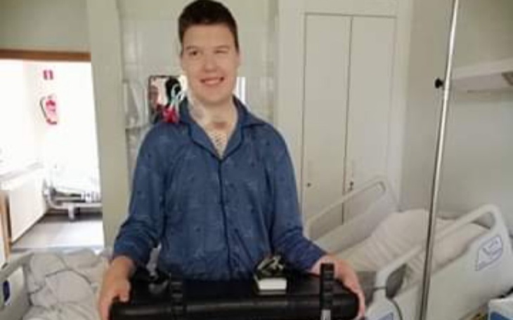 Młody mężczyzna trzymający walizkę w szpitalnym łóżku.