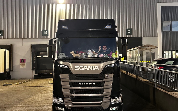 Ciężarówka Scania z pluszakami na przedniej szybie, w nocy.