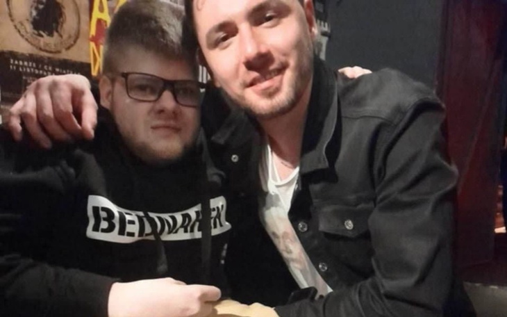 Dwóch mężczyzn przytulających się w barze, uśmiechnięte twarze.