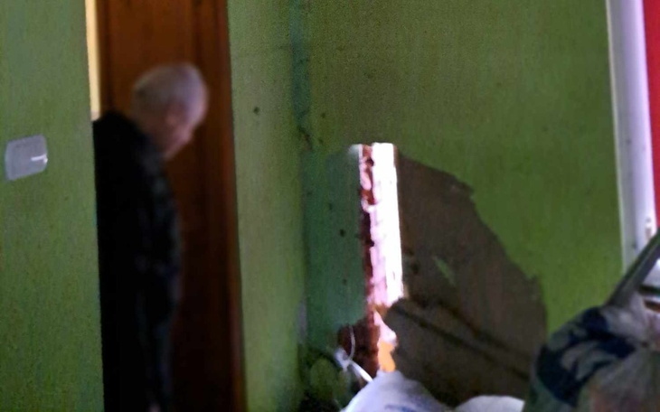 Dziura w ścianie z widocznym mężczyzną w tle.