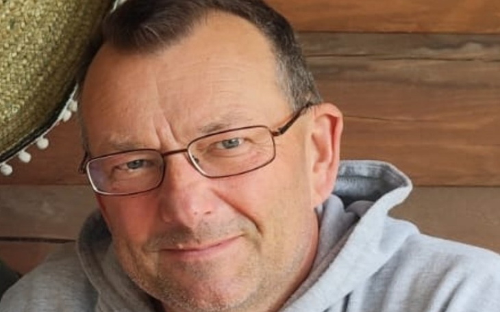 Mężczyzna w okularach, uśmiechający się do kamery.