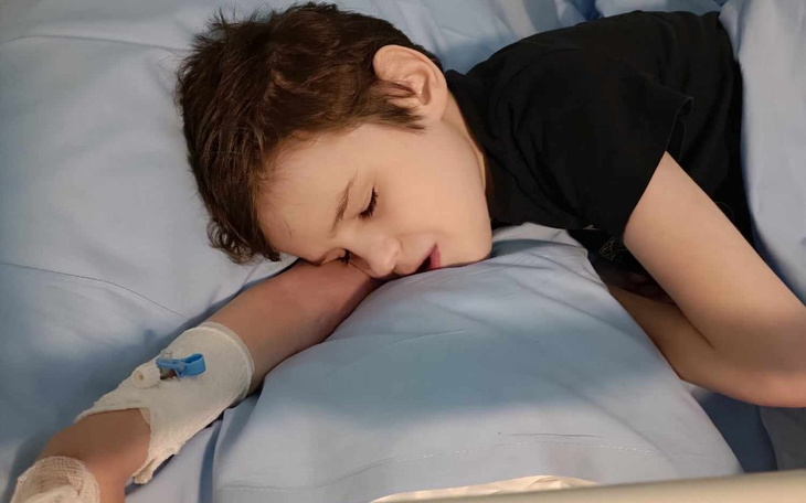 Chłopiec śpiący w szpitalnym łóżku, opatrunek na ręce.