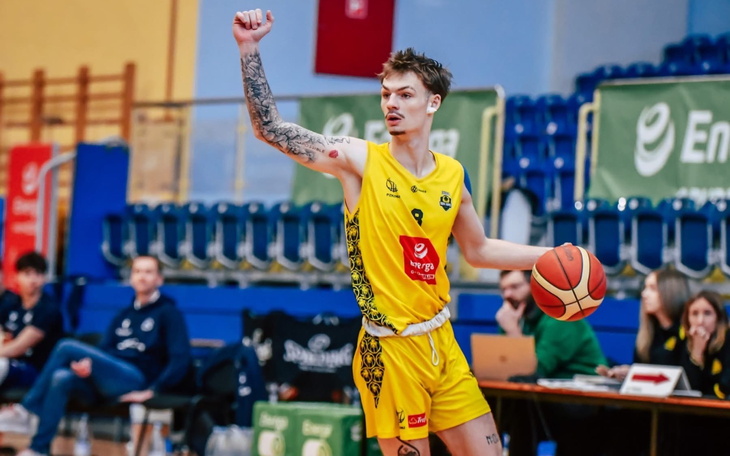 Koszykarz w akcji, z uniesioną ręką na boisku.