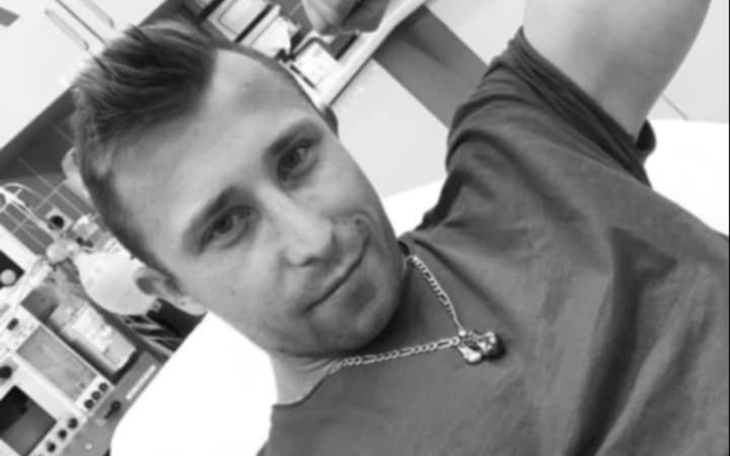 Mężczyzna w szarej koszulce leży na łóżku w szpitalu.