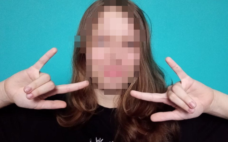 Młoda osoba z zamazanym wizerunkiem pokazująca znak pokoju.