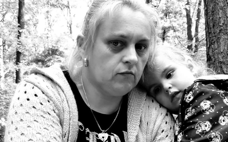 Matka z dzieckiem w lesie, wyraz smutku na twarzy.