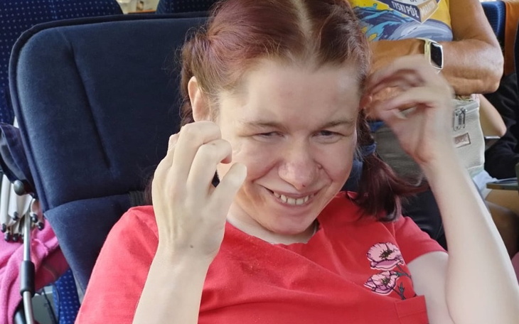 Uśmiechnięta kobieta w czerwonej koszulce, siedząca w fotelu.