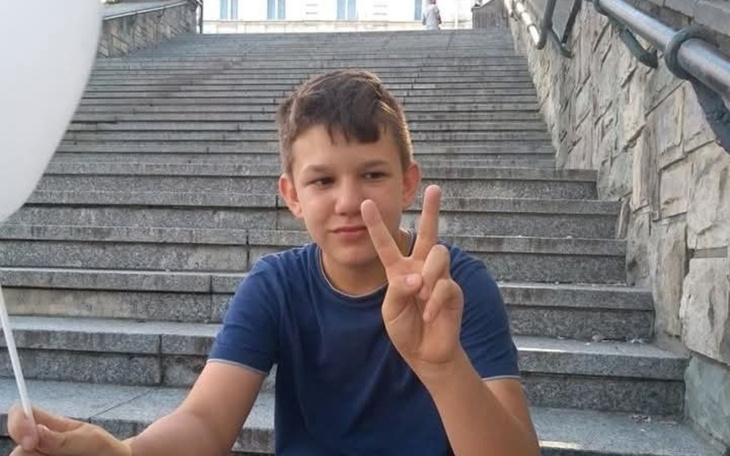 Młody chłopak pokazujący znak pokoju na schodach.