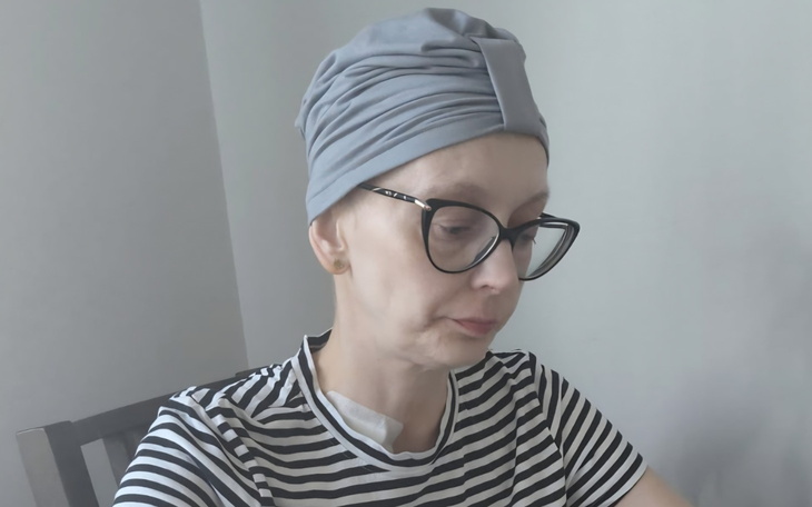 Kobieta w chustce, skupiona na pracy przy stole.