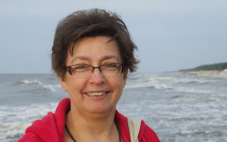 Kobieta uśmiechająca się na plaży, w tle fale.