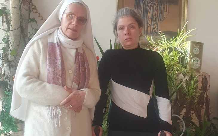 Dwie kobiety w jasnym otoczeniu, jedna w habicie, druga w czarnym swetrze.