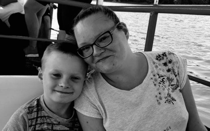 Matka z synem, oboje uśmiechnięci na tle wody.