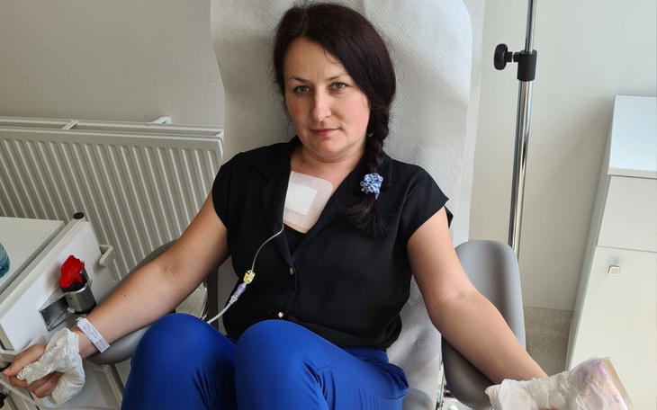 Kobieta w trakcie leczenia, siedząca w fotelu z kroplówką.