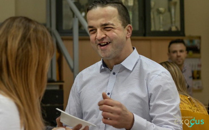 Mężczyzna uśmiechający się podczas rozmowy w grupie.